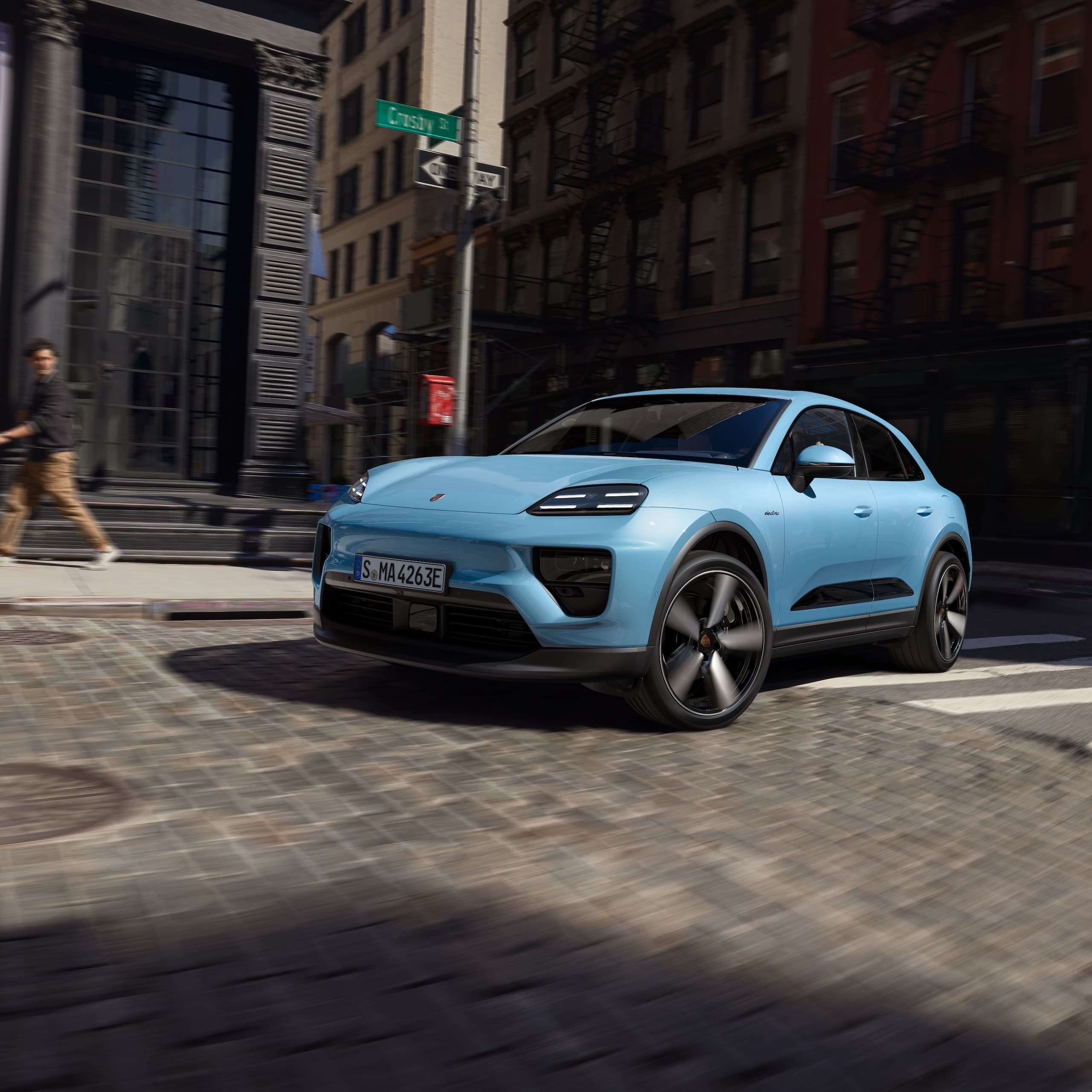 Un Porsche totalmente eléctrico Macan conduciendo por una carretera en un escenario urbano.